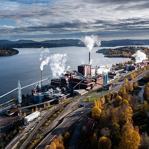 Foto av Mondi Dynäs fabrik med vatten i förgrunden