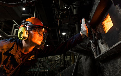 Person with helmet looking into machine